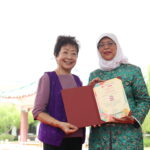 President Halimah Yacob presenting a certificate of appreciation to Singapore Women's Association